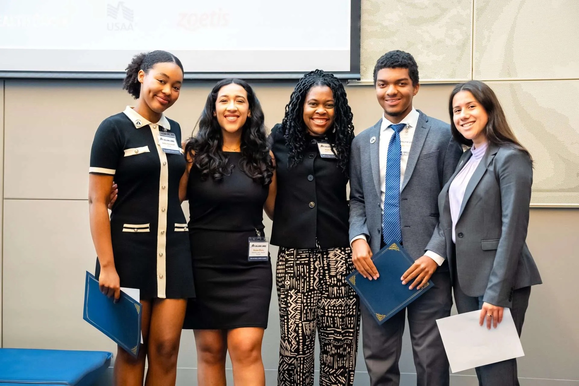 Five people posing together at an INROADS career event, several holding presentation folders