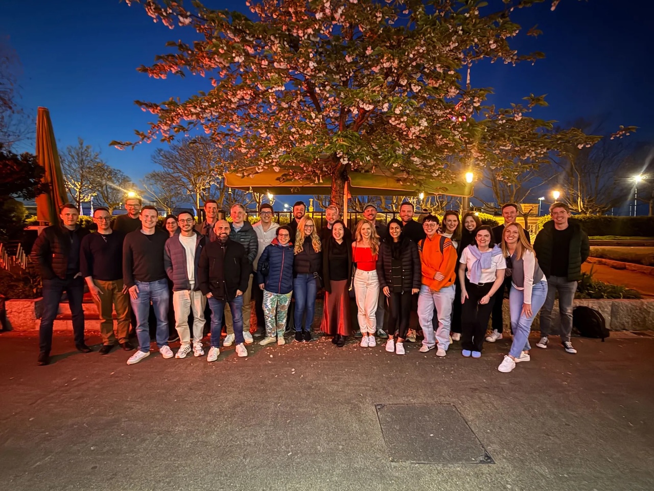 Members of the Inscribe team gathered outdoors at dusk beneath a flowering tree