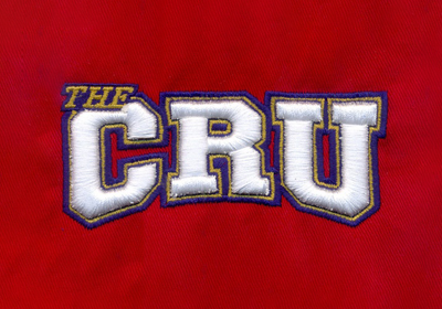 Raised white CRU lettering with colored outlines on red fabric, from Inscribe’s embroidery portfolio