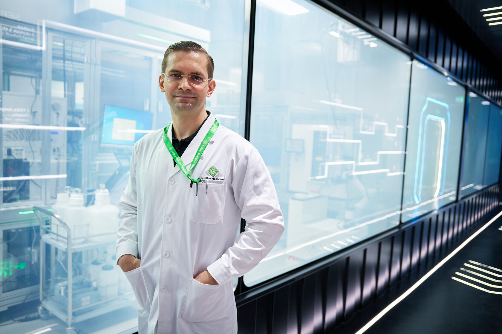 Alex Zhavoronkov wearing a lab coat beside glass-enclosed equipment in Insilico’s Suzhou robotics laboratory