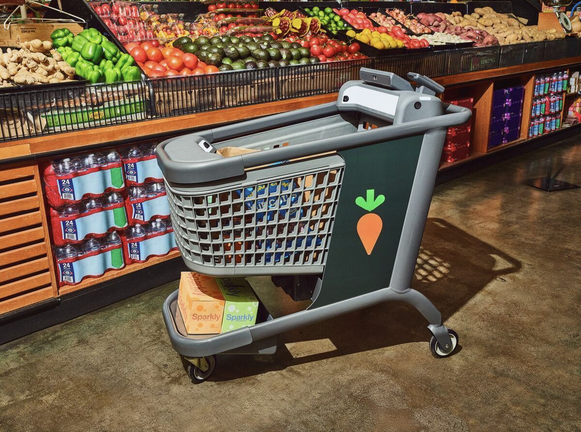 Instacart Caper smart shopping cart beside supermarket produce displays