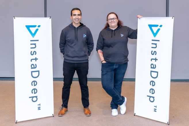 InstaDeep co-founders Karim Beguir and Zohra Slim standing between company banners
