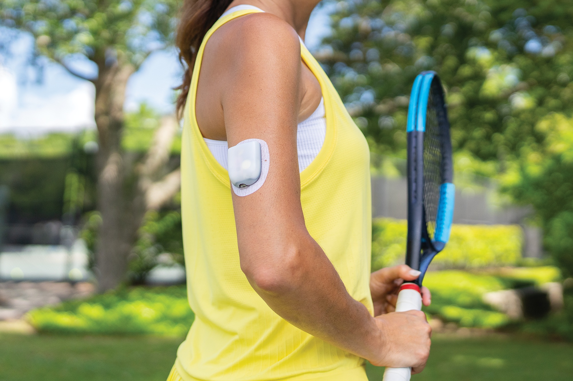 Person on a tennis court wearing an Omnipod 5 Pod and holding its controller