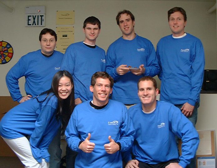Seven members of the early Intapp team wearing matching blue Tsunami shirts in 2003