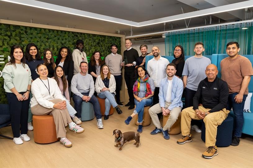 Integral Ad Science employees gathered in an office lounge, with a small dachshund in front