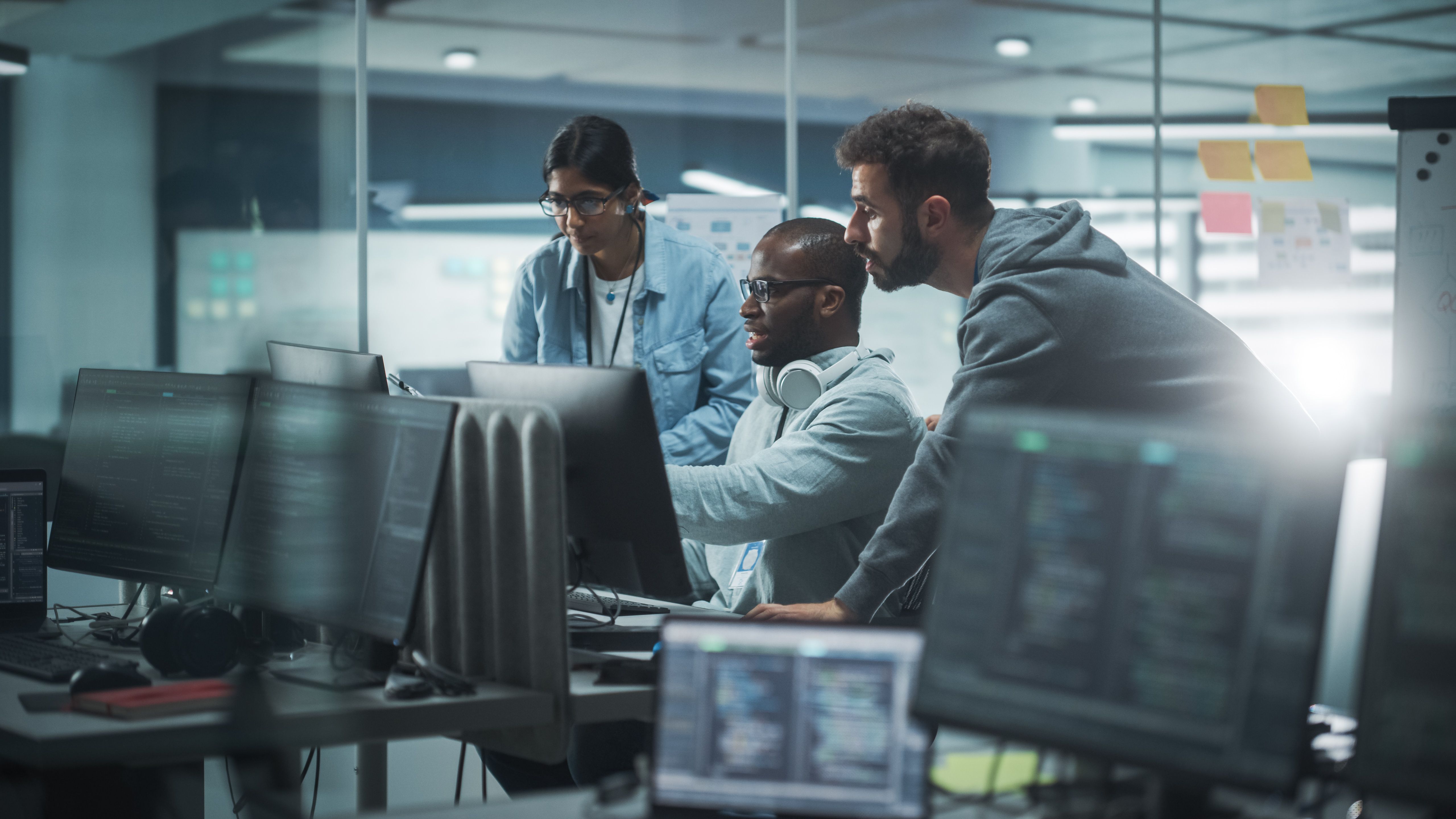 Illustrative office scene with three people reviewing computer screens