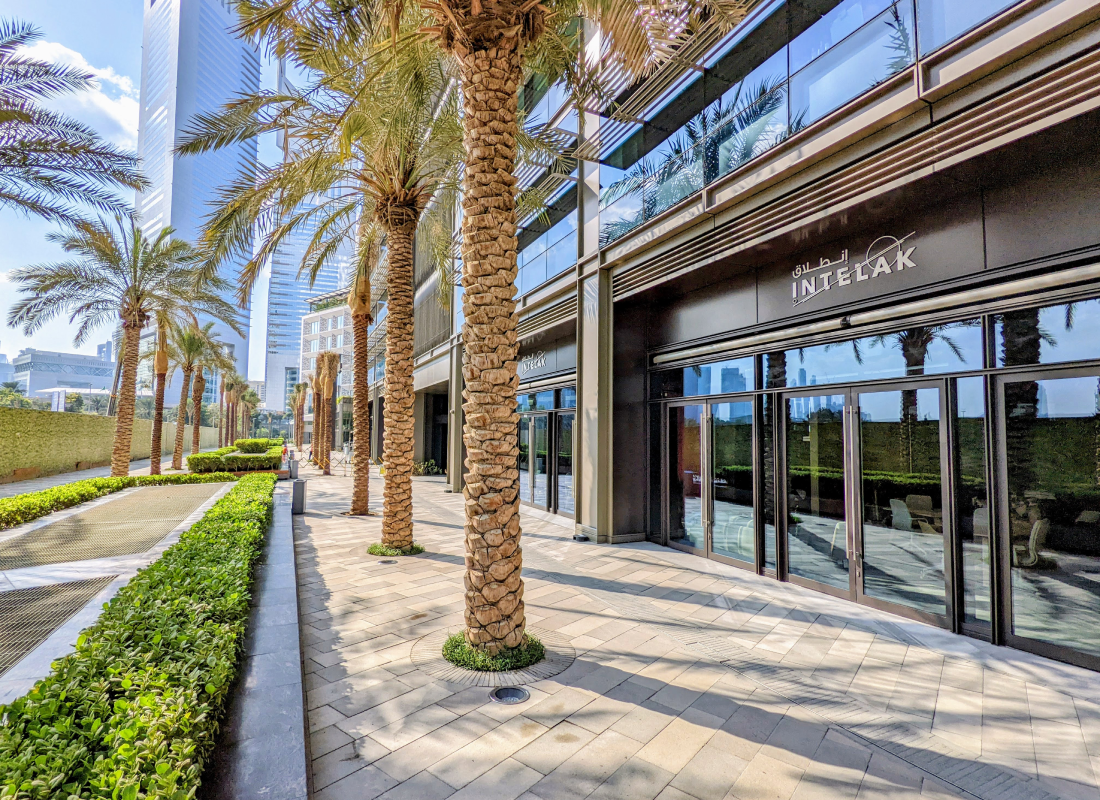 Intelak’s glass-fronted Dubai premises with palm trees along the pavement.