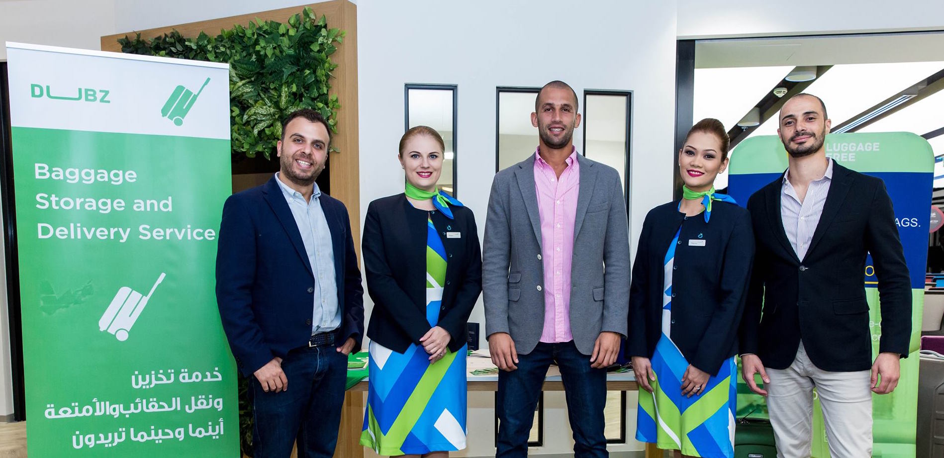 Five people stand beside DUBZ baggage service displays in a photograph published with Intelak’s 2018 dnata acquisition announcement.