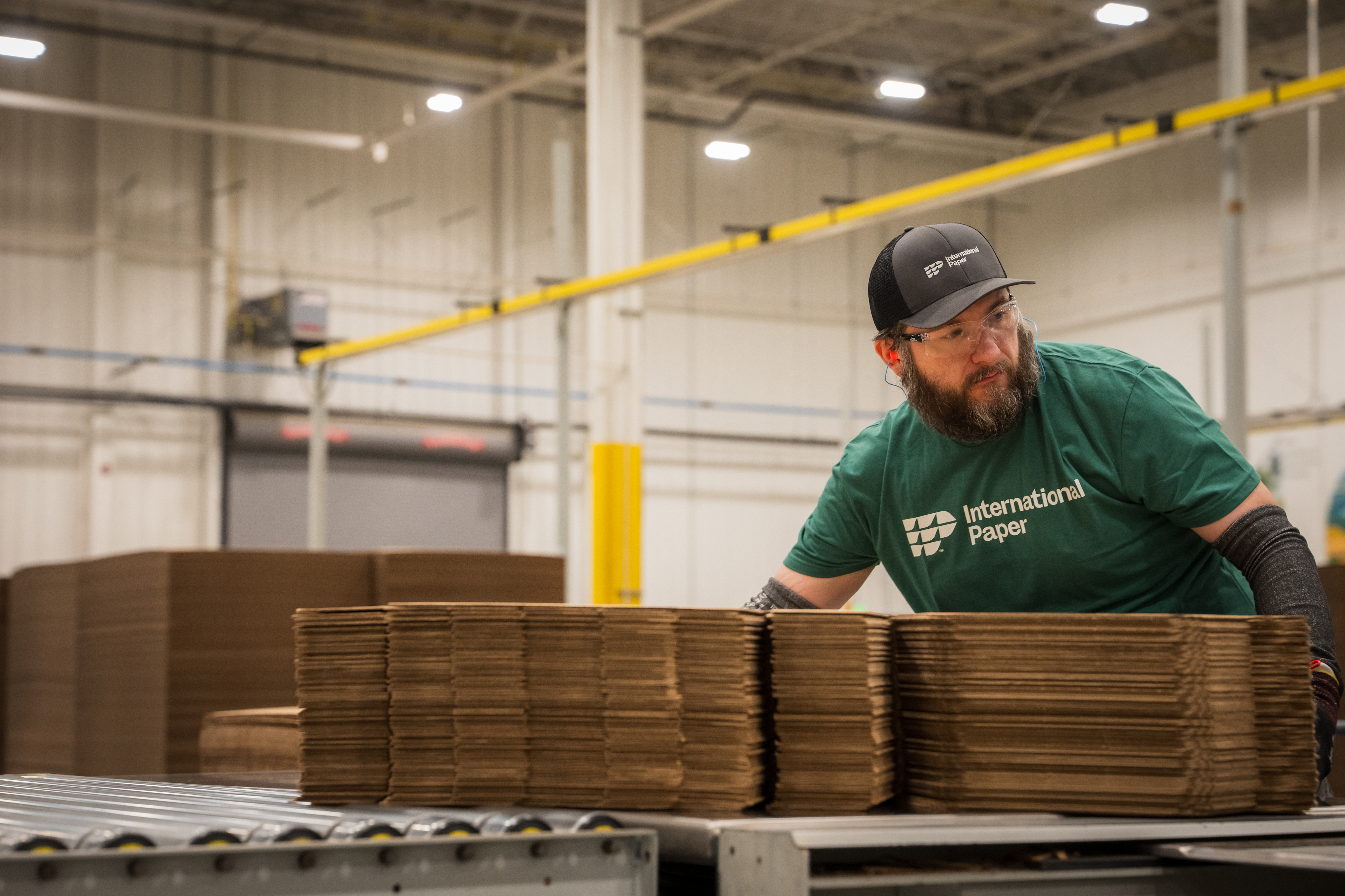 International Paper employee guiding flattened corrugated boxes along a conveyor
