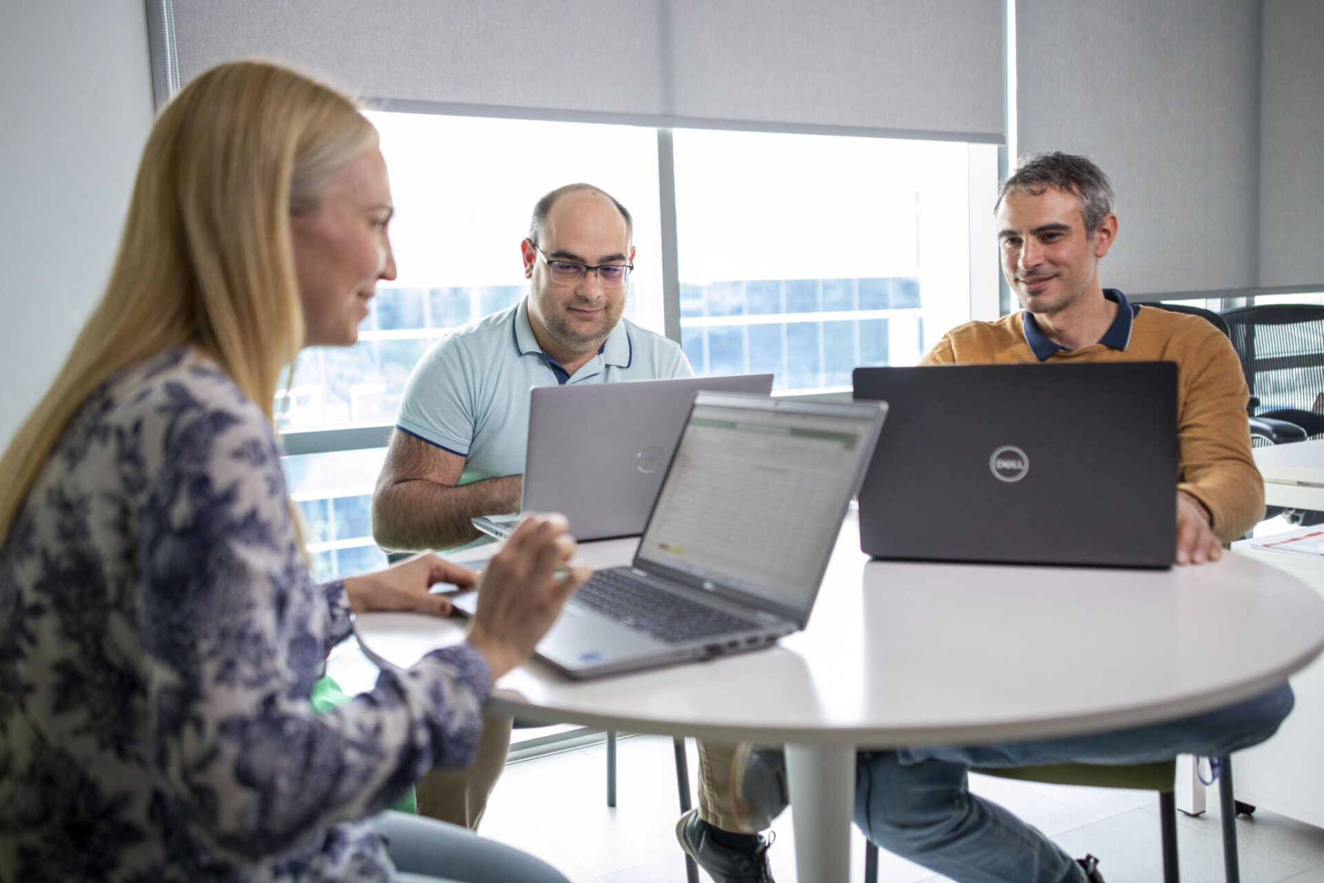 Three colleagues working together around a table with laptops in an interop.io office photograph