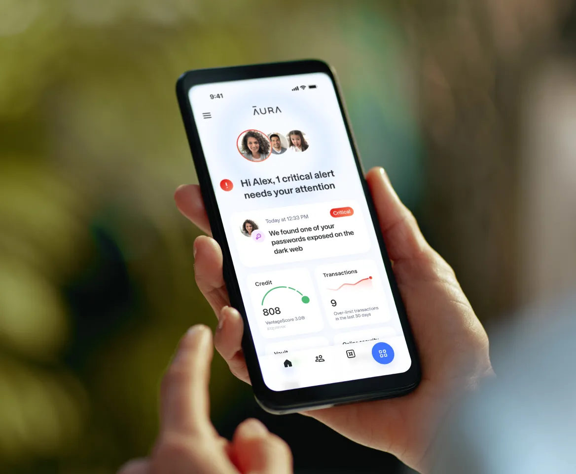 A hand holding a phone displaying the Aura app dashboard