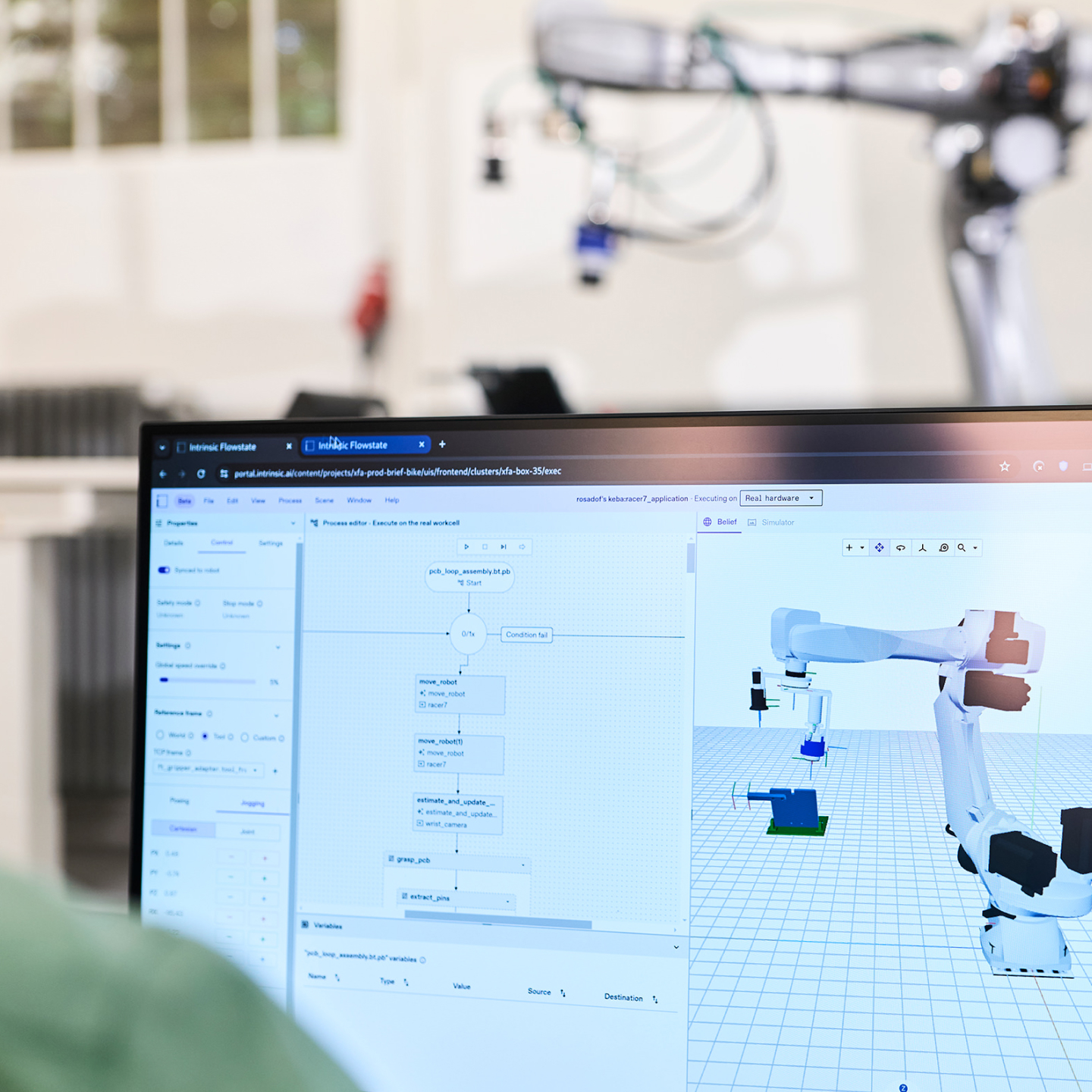 A monitor showing Intrinsic Flowstate beside the physical industrial robot represented in the software