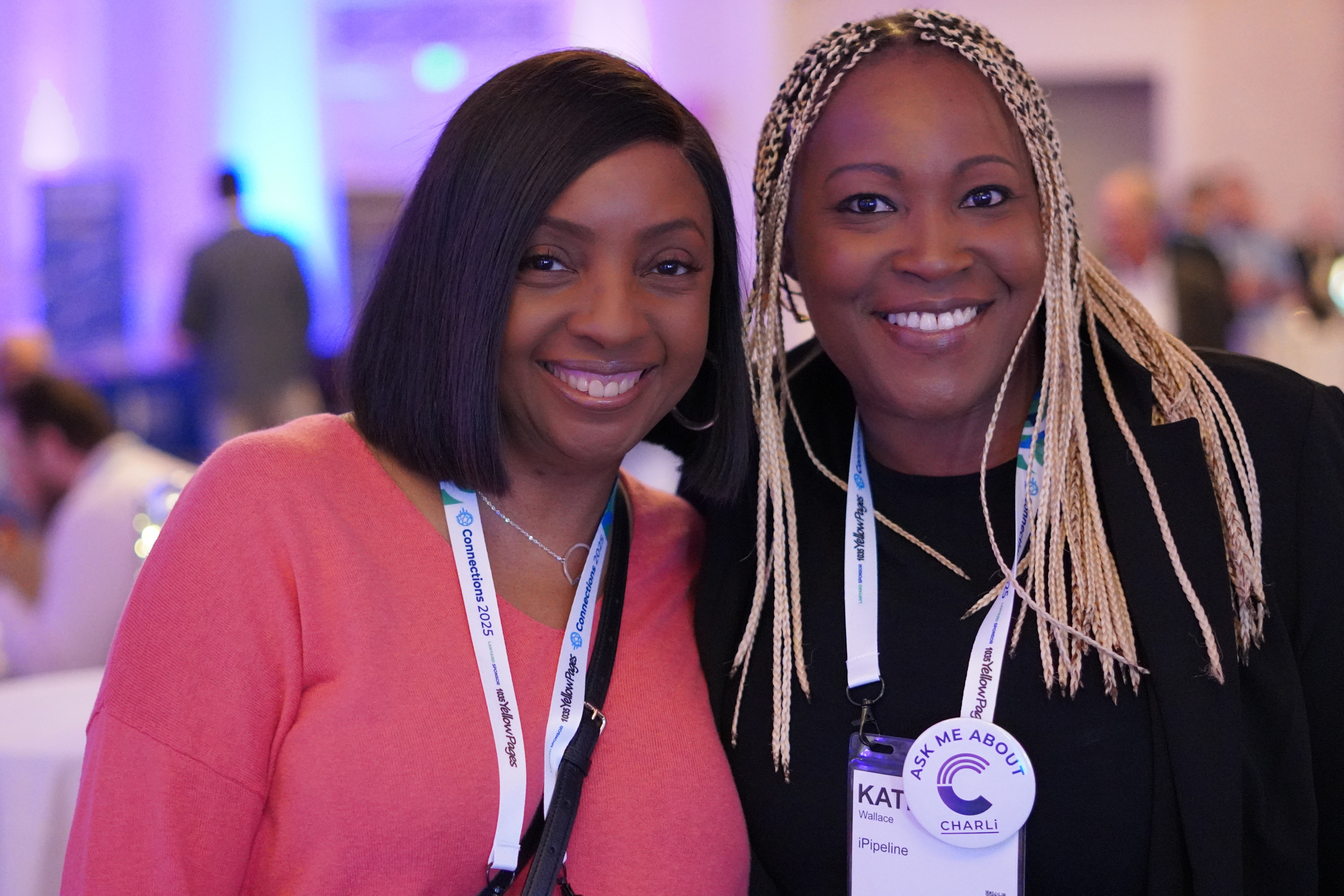 Two attendees at iPipeline’s Connections 2025 conference; a CHARLi badge is visible.