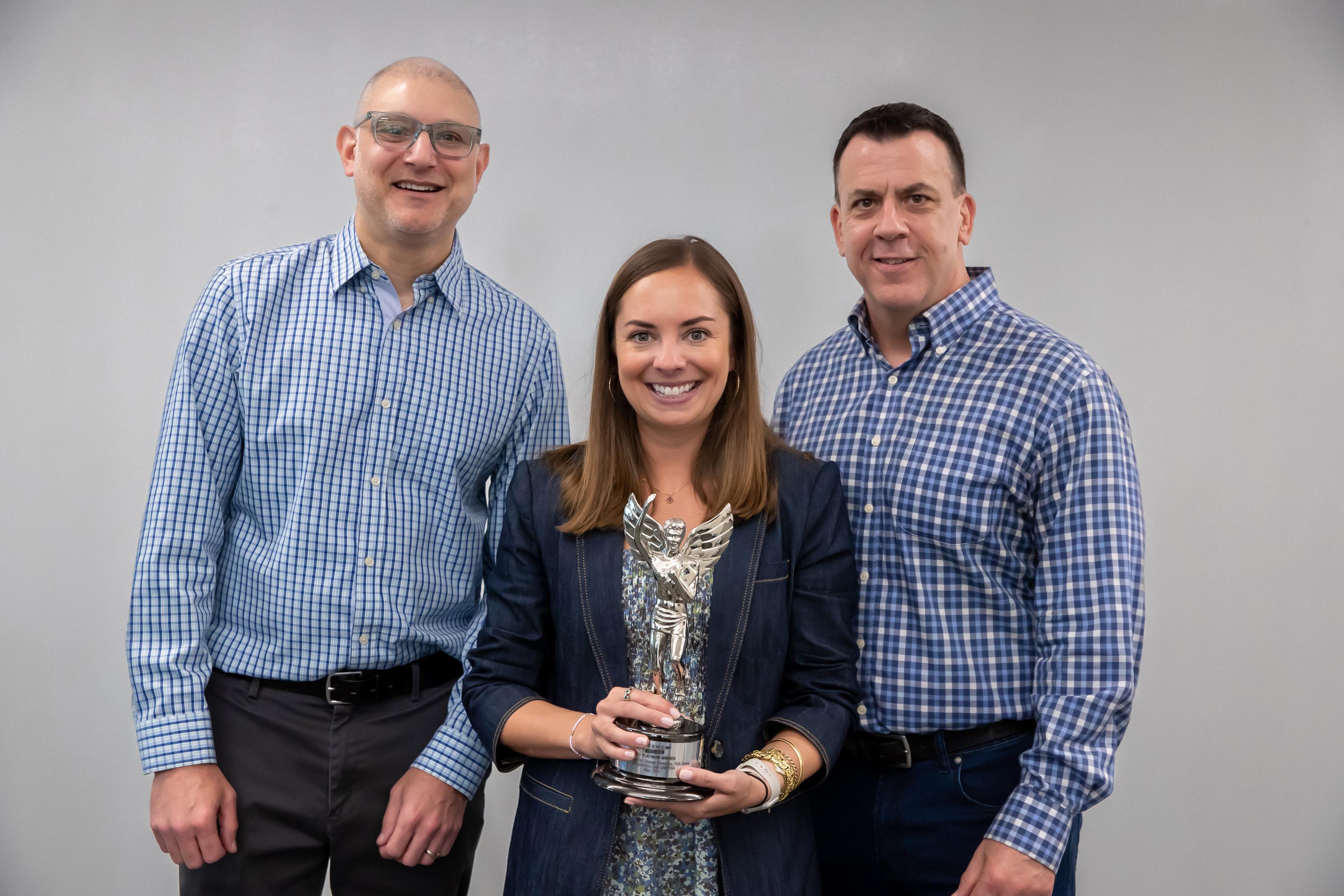 Three IQ Solutions team members smiling together at an awards event
