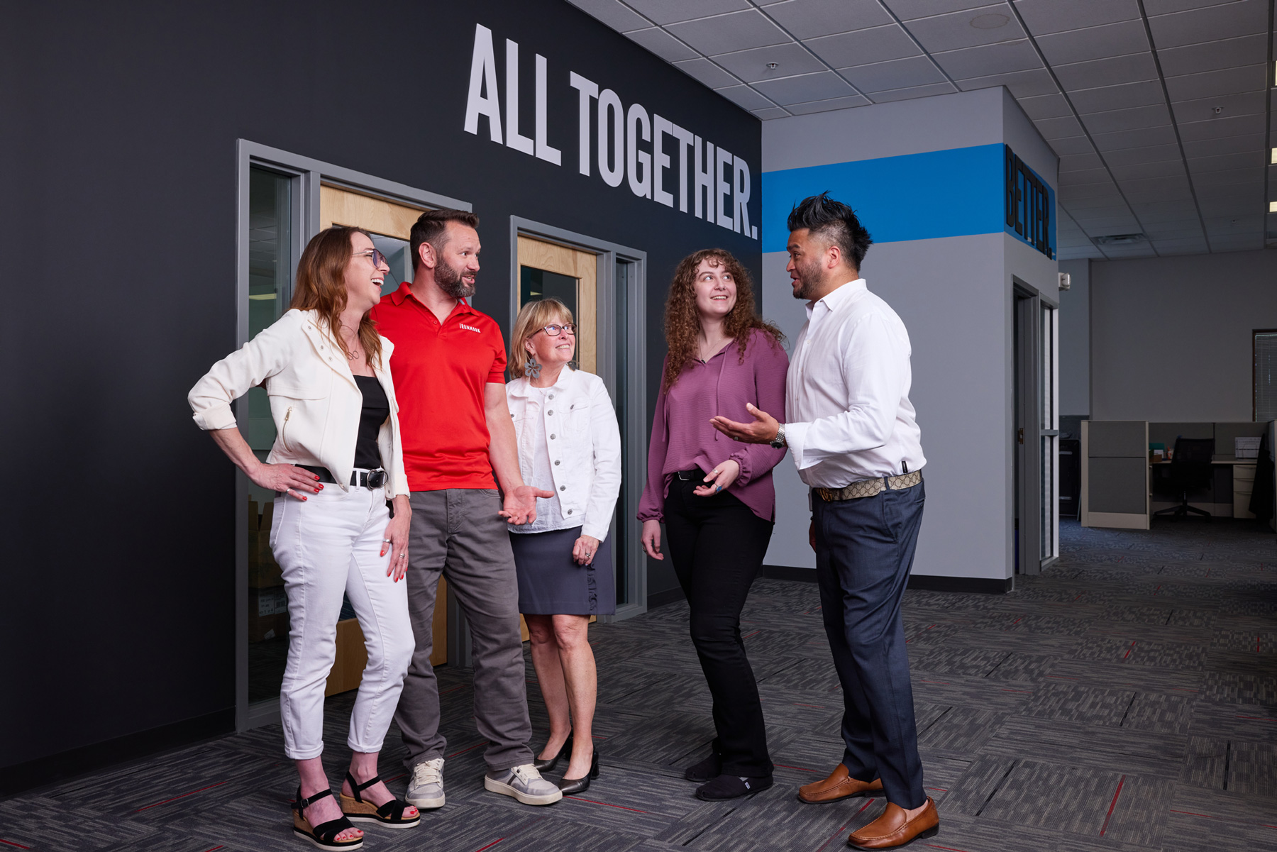 Ironmark team members talking beneath an All Together wall graphic