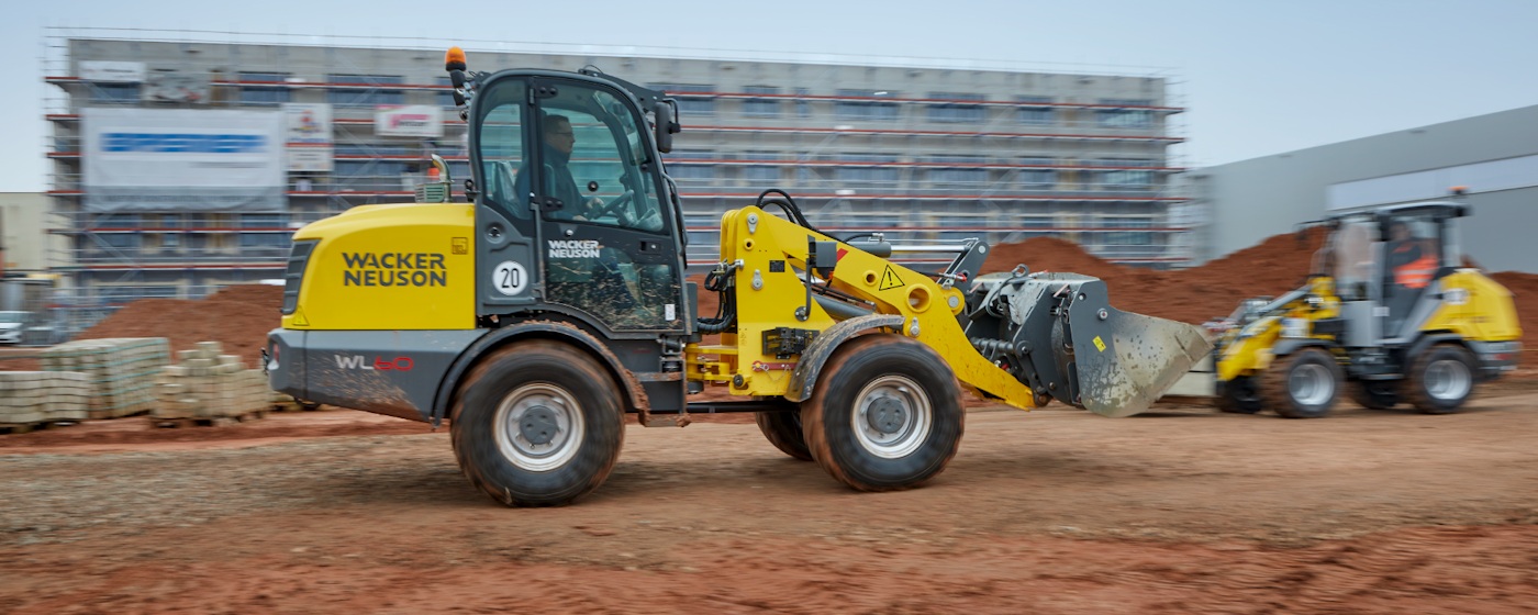 A yellow Wacker Neuson WL60 wheel loader carrying material on a construction site