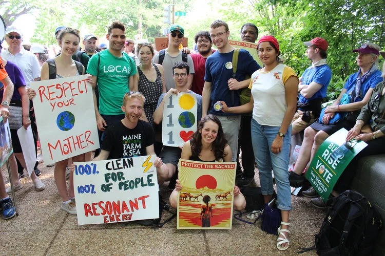 An early Resonant Energy group at a public climate gathering holding handmade clean-energy signs