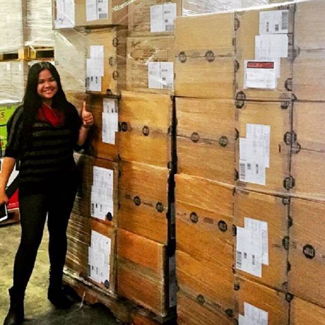 Ishka Villacisneros standing beside stacks of wrapped shipping crates