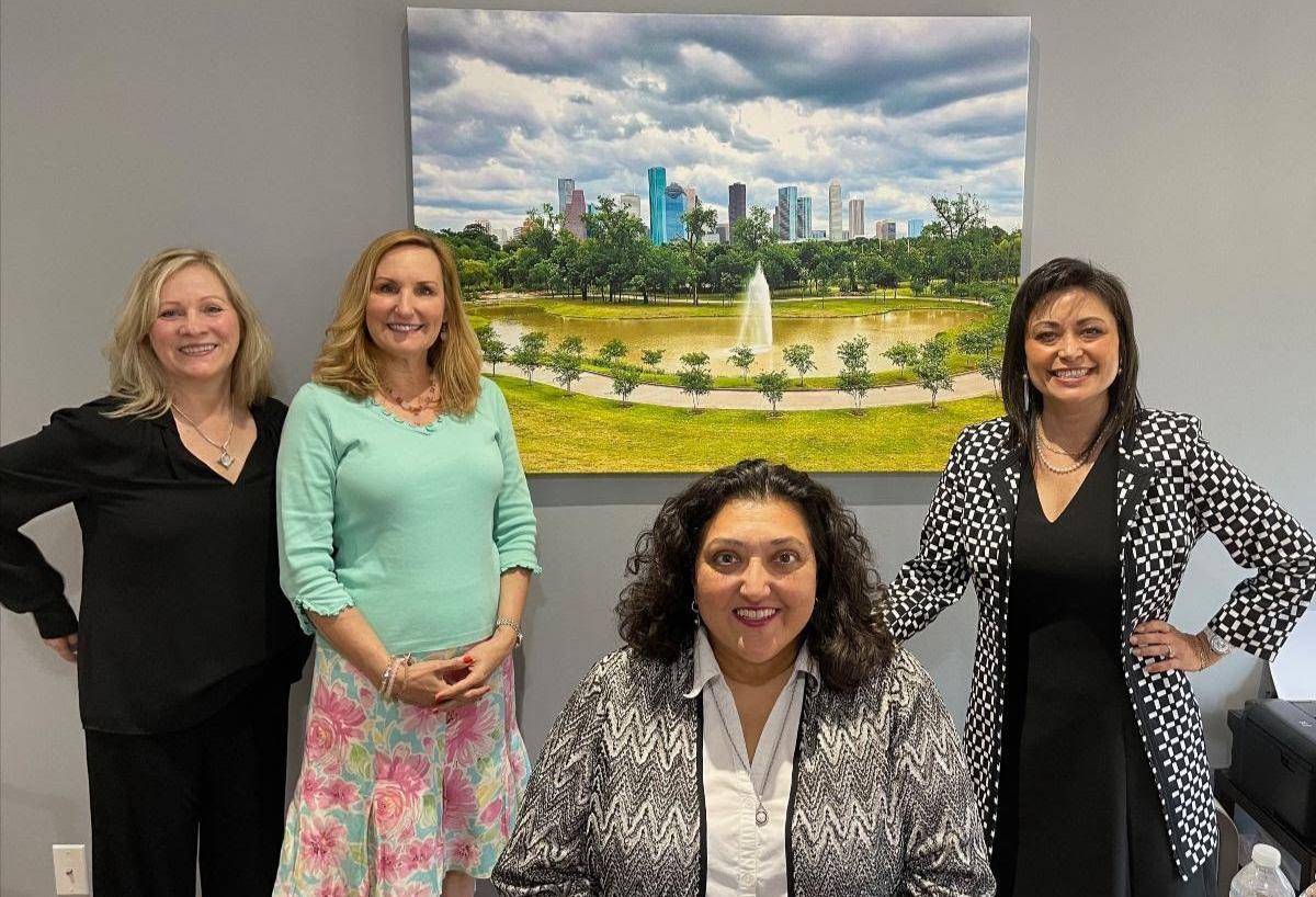 Ishnella Azad with friends celebrating her Houston office, with a cityscape artwork behind them