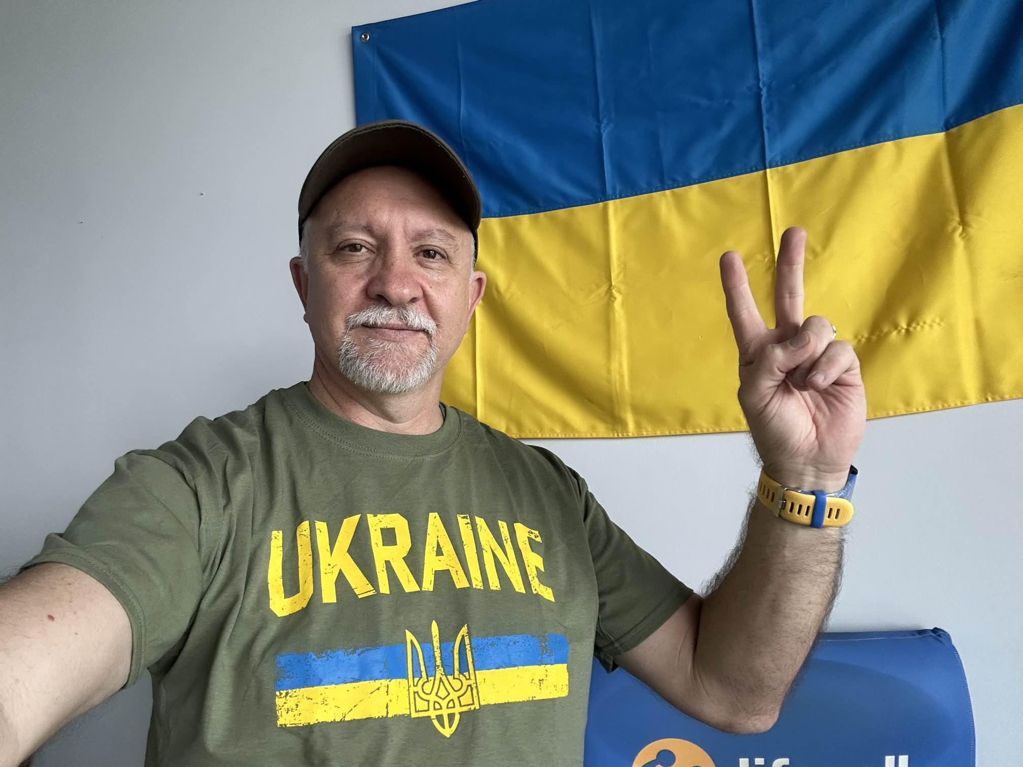 Ismet Yazici wearing a Ukraine T-shirt and raising two fingers in front of a Ukrainian flag
