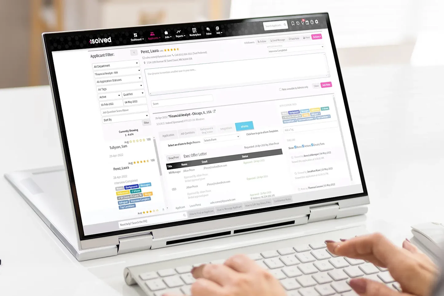 Official product photograph showing the isolved applicant tracking interface on a laptop