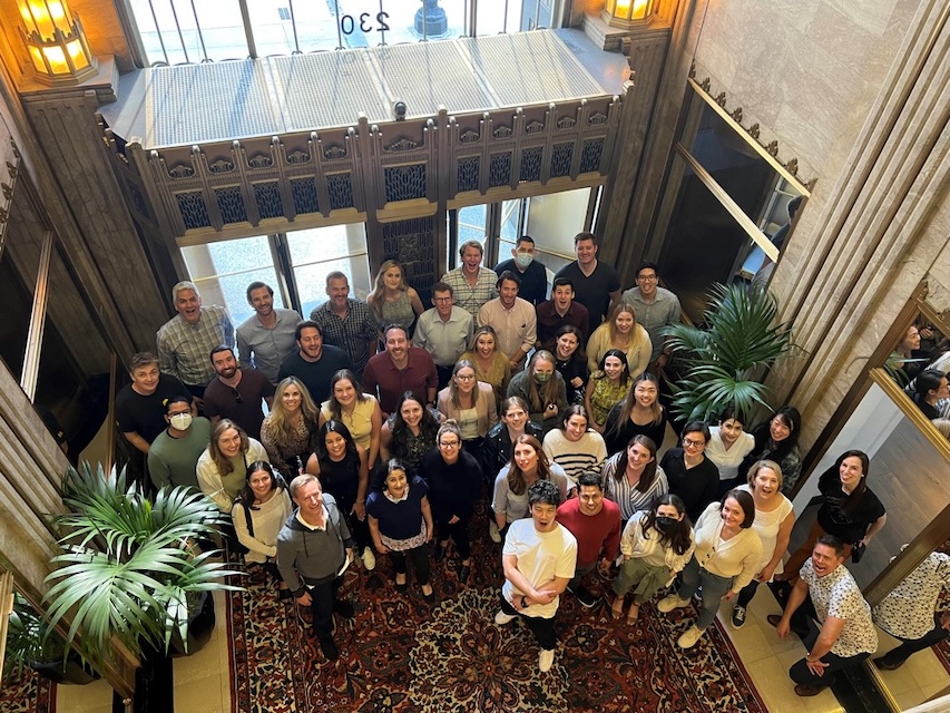 iSpot colleagues gathered in a lobby, looking up toward the camera