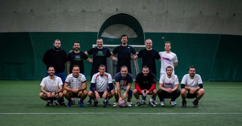 IT Labs colleagues pose in two rows in front of a football goal