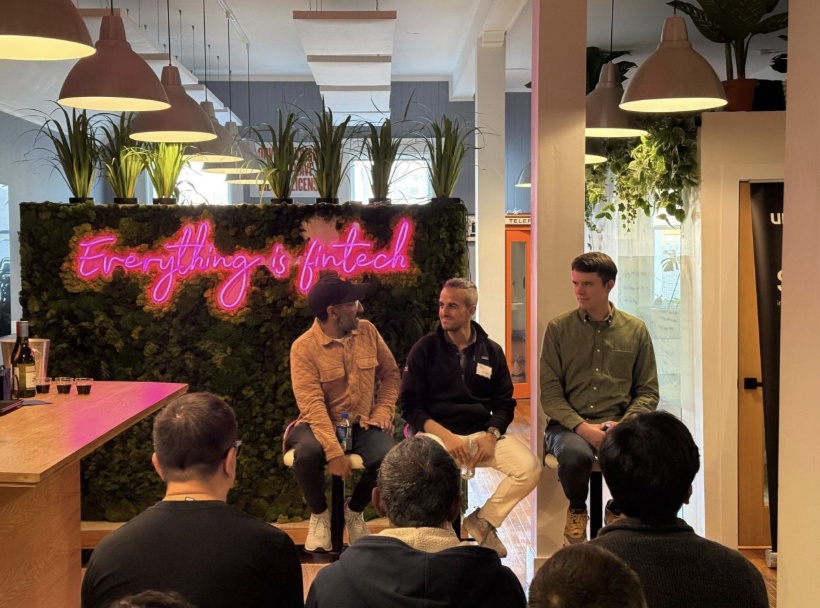 Three speakers seated in front of a pink Everything is fintech sign at the Better Tomorrow Ventures fireside conversation