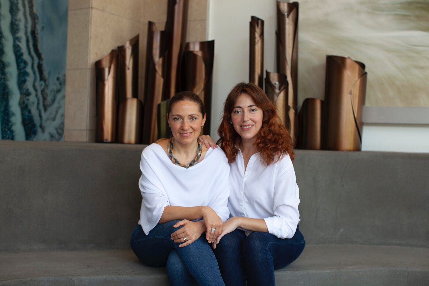 Iva Teixeira, left, and Lena Skliarova-Mordvinova seated together, wearing white tops and jeans.