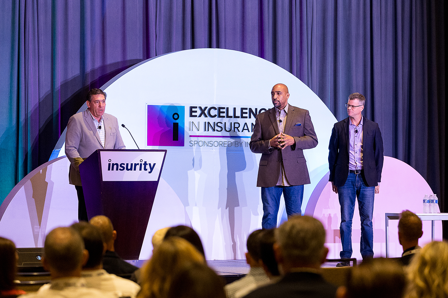 Ivan Latanision and fellow Insurity executives speaking onstage at an insurance conference