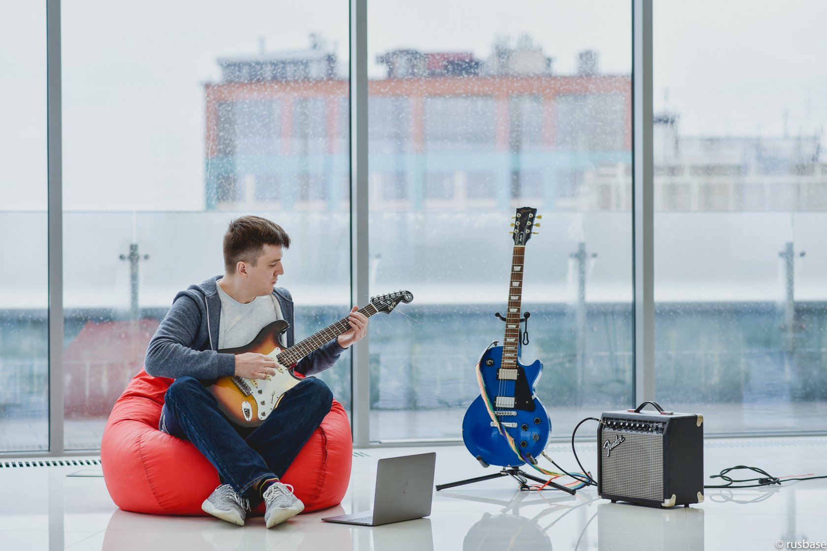 Ivan Tsybaev seated on a red beanbag playing an electric guitar in the Trucker Path office