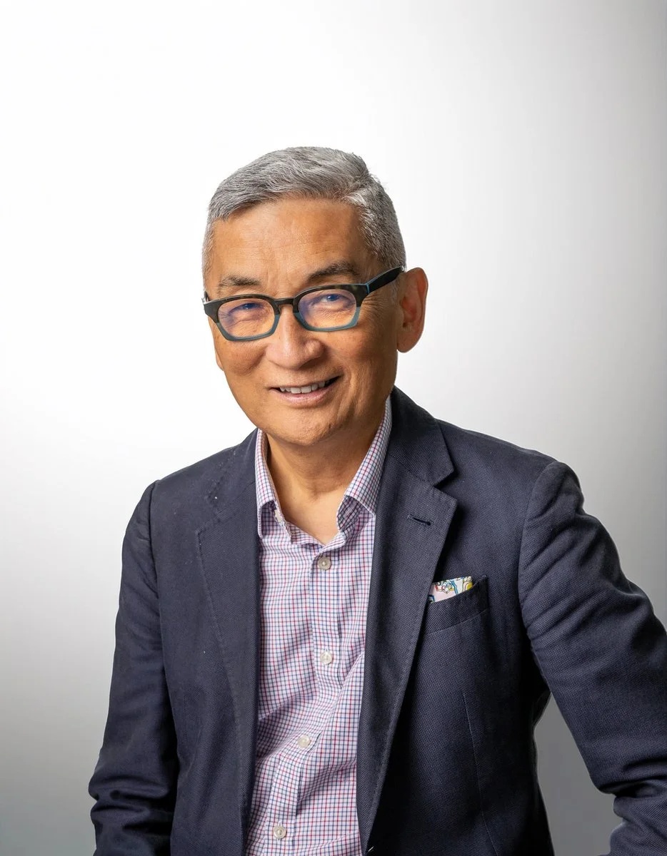 Portrait of IW Group co-founder Bill Imada, wearing glasses and a dark blazer