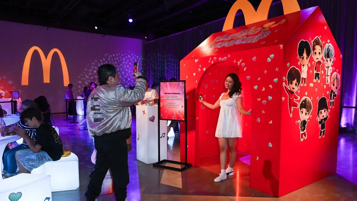 Fans pose beside an oversized red Happy Meal box at the TinyTAN event