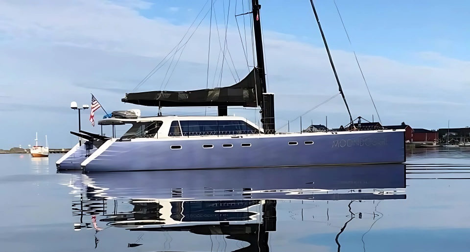 Moondoggie, the Romm family's sailing catamaran, reflected in calm harbor water