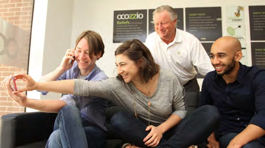 Russ Krueger standing behind three smiling Ocozzio colleagues in a group photograph