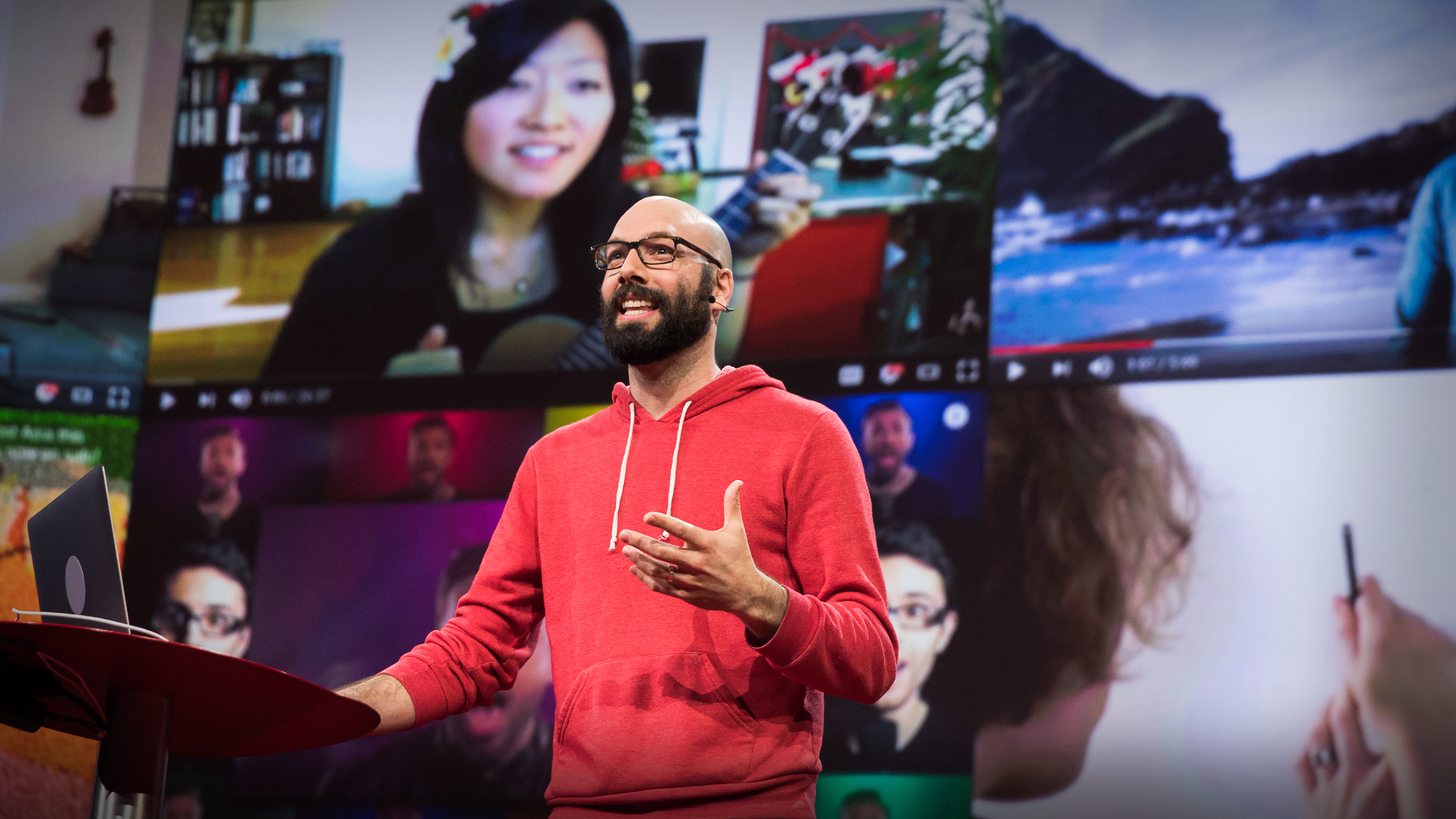 Jack Conte in a red hoodie speaking on the TED stage, with creator videos projected behind him