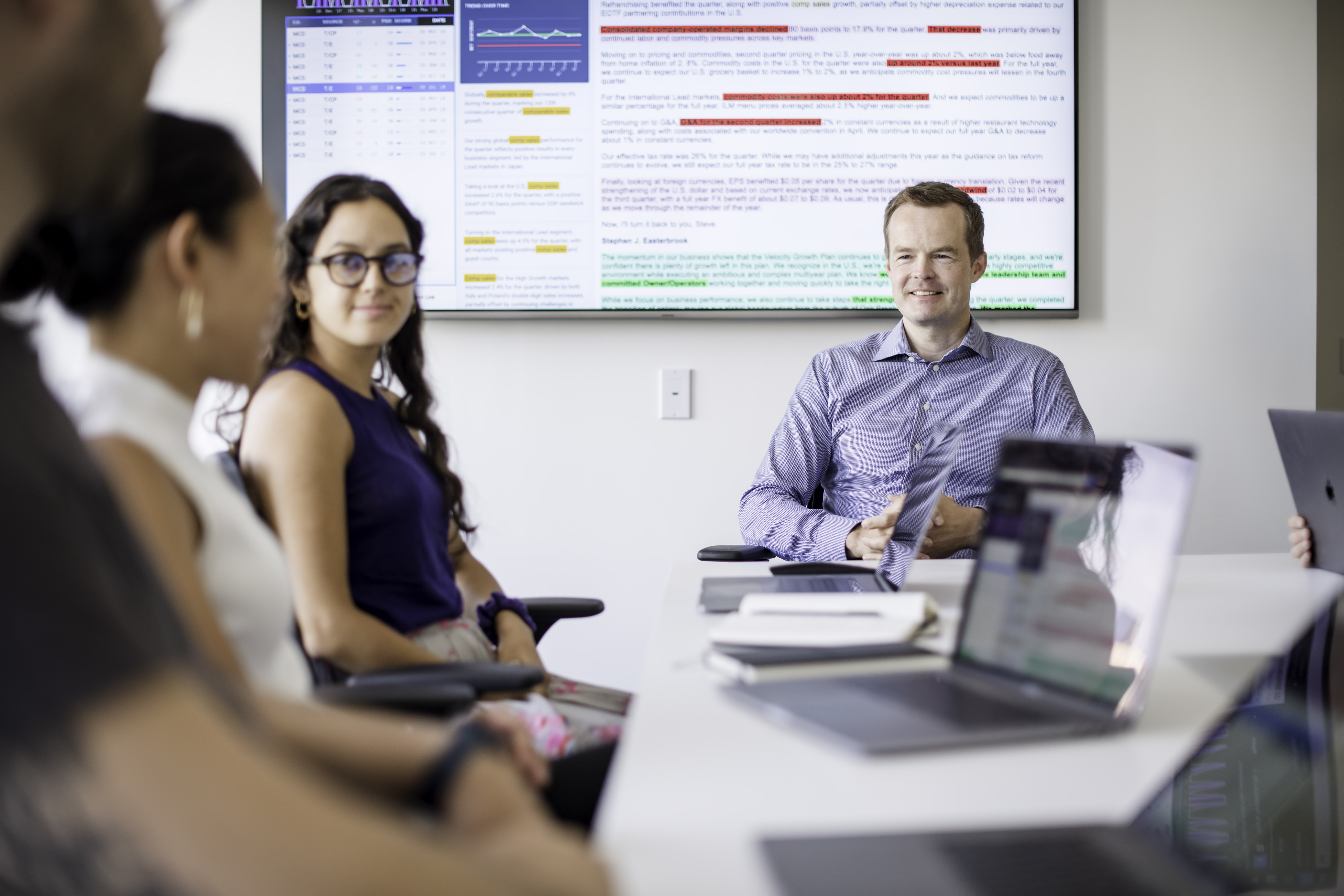 Jack Kokko seated with colleagues around an office meeting table, with a research screen behind them