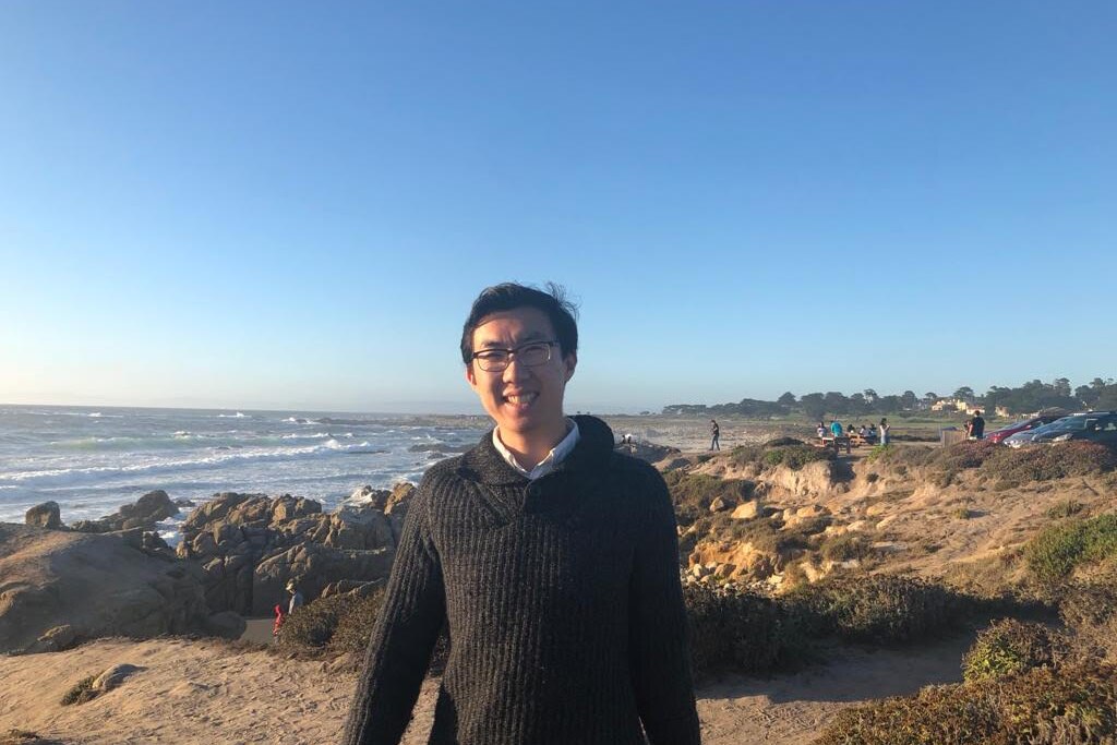 Jack Lu standing beside a rocky coastline