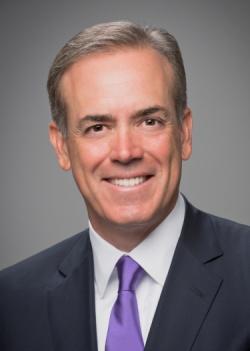 Archival photograph of Jack McDonald wearing a dark suit and purple tie