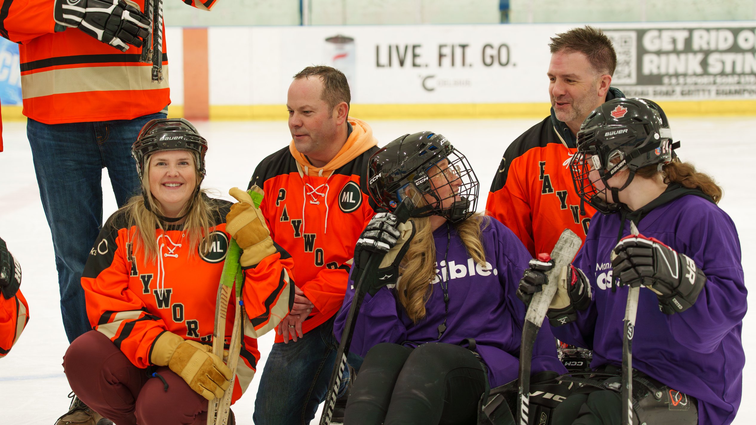 Jaclyn Christie, at left, sits on the ice with Payworks colleagues and Manitoba Possible participants after a sledge hockey session.
