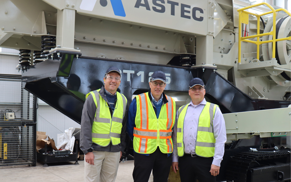 Jaco van der Merwe and colleagues wearing high visibility vests beside Astec equipment inside the Omagh factory