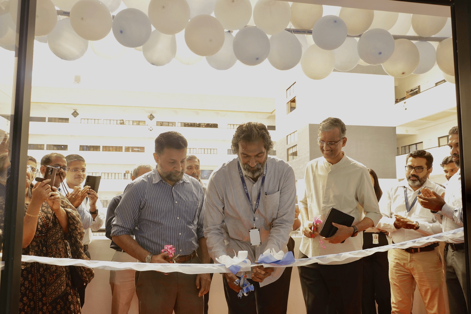 Jacob Aruldhas cuts a ribbon at the ECS Fin office opening in Technopark, surrounded by colleagues.