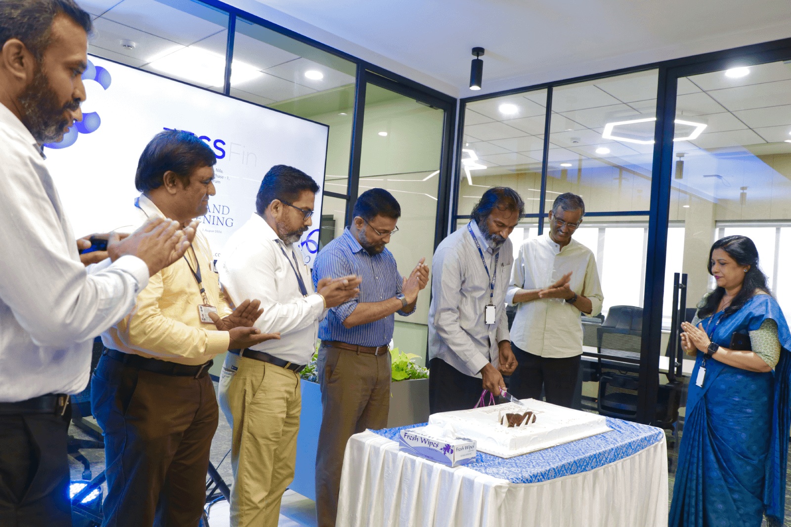 Colleagues gather for a cake-cutting celebration at the new ECS Fin office.