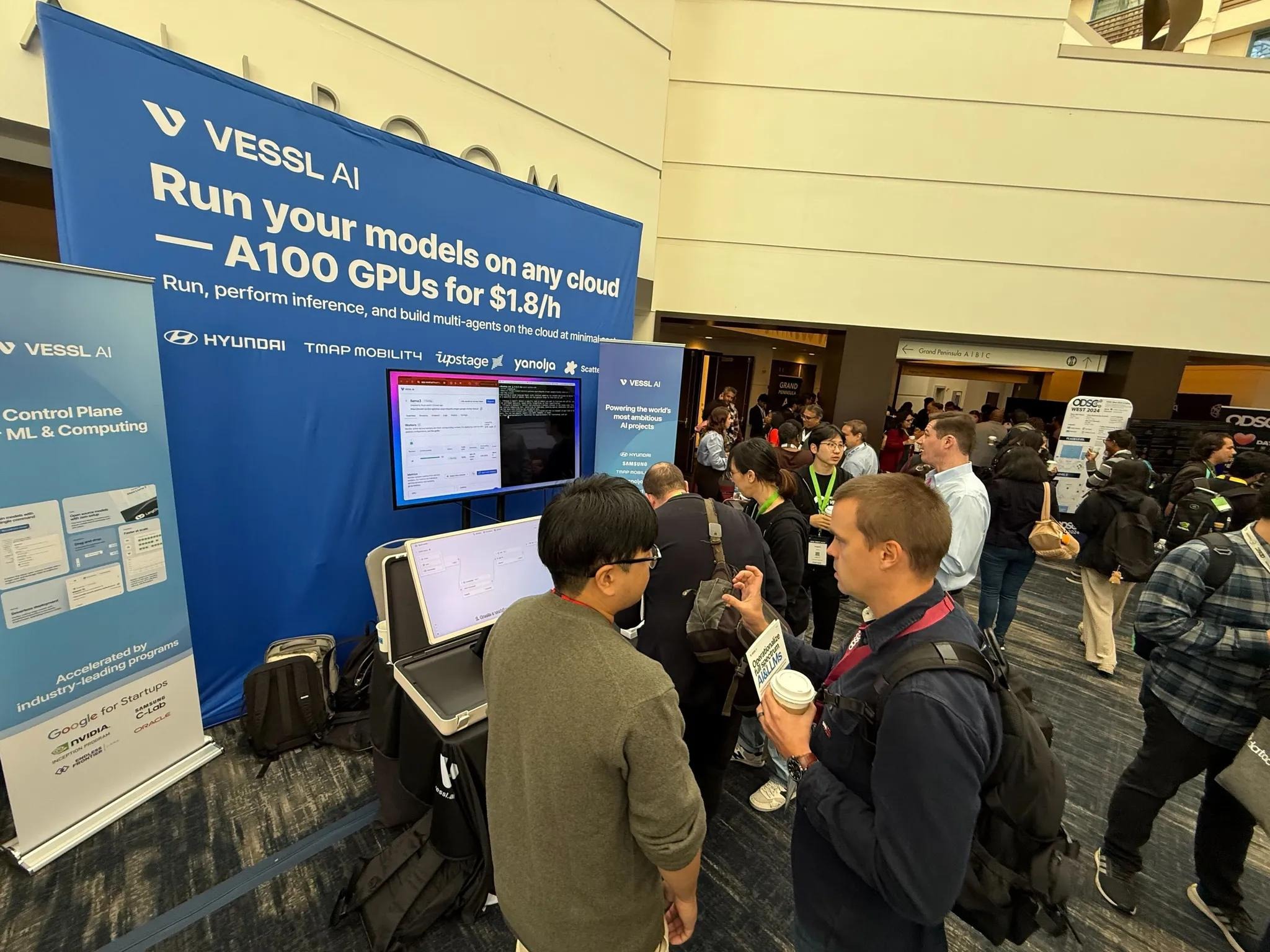 VESSL AI booth at ODSC West 2024, where attendees gather around a live infrastructure demonstration