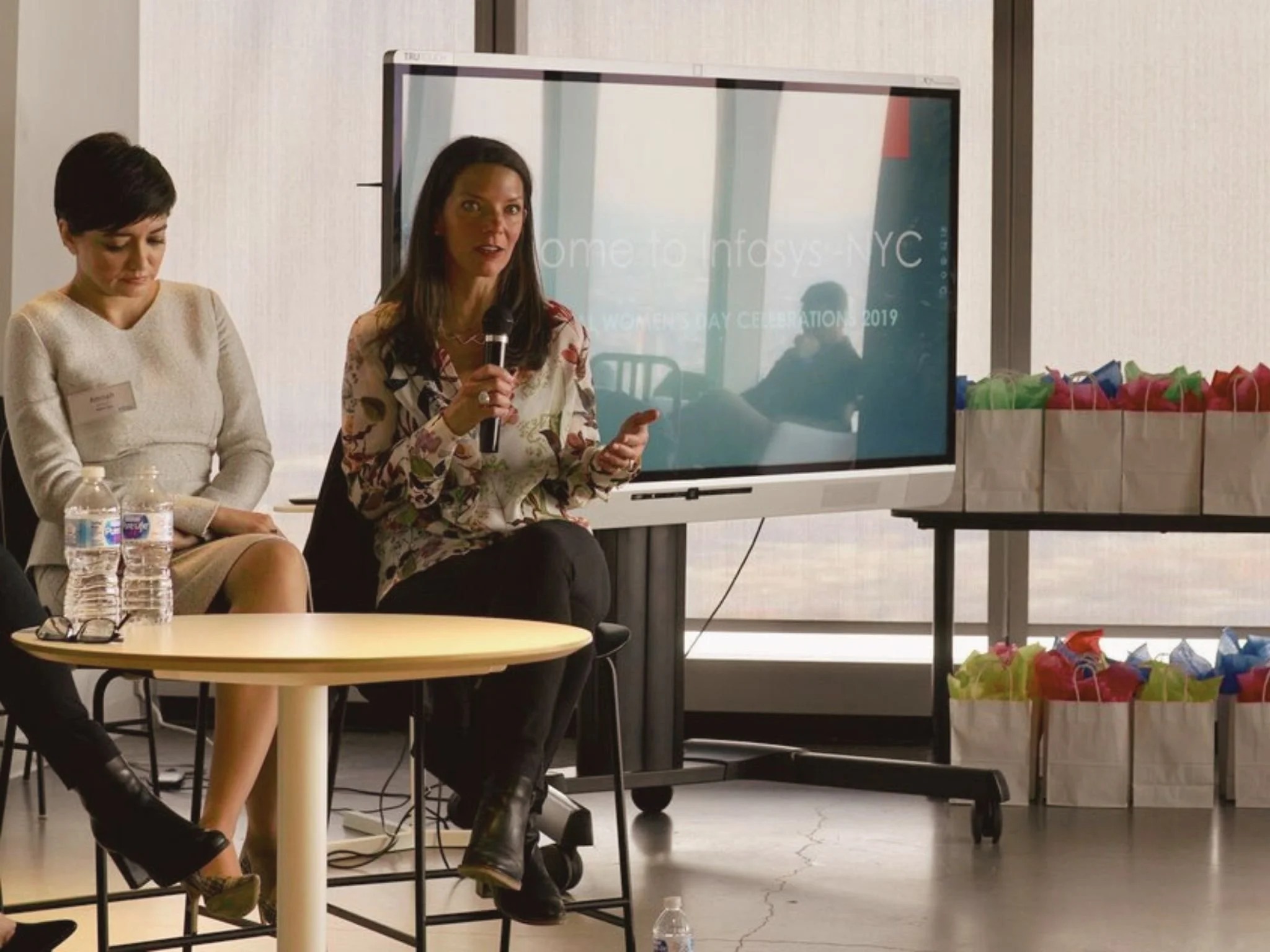 Jahn Marie Surette speaking into a microphone during a women-focused event at Infosys in New York