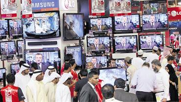A crowded electronics retail floor in Dubai in 2009, with shoppers gathered around television displays