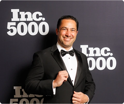 Jaime Nacach in a tuxedo in front of an Inc. 5000 event backdrop