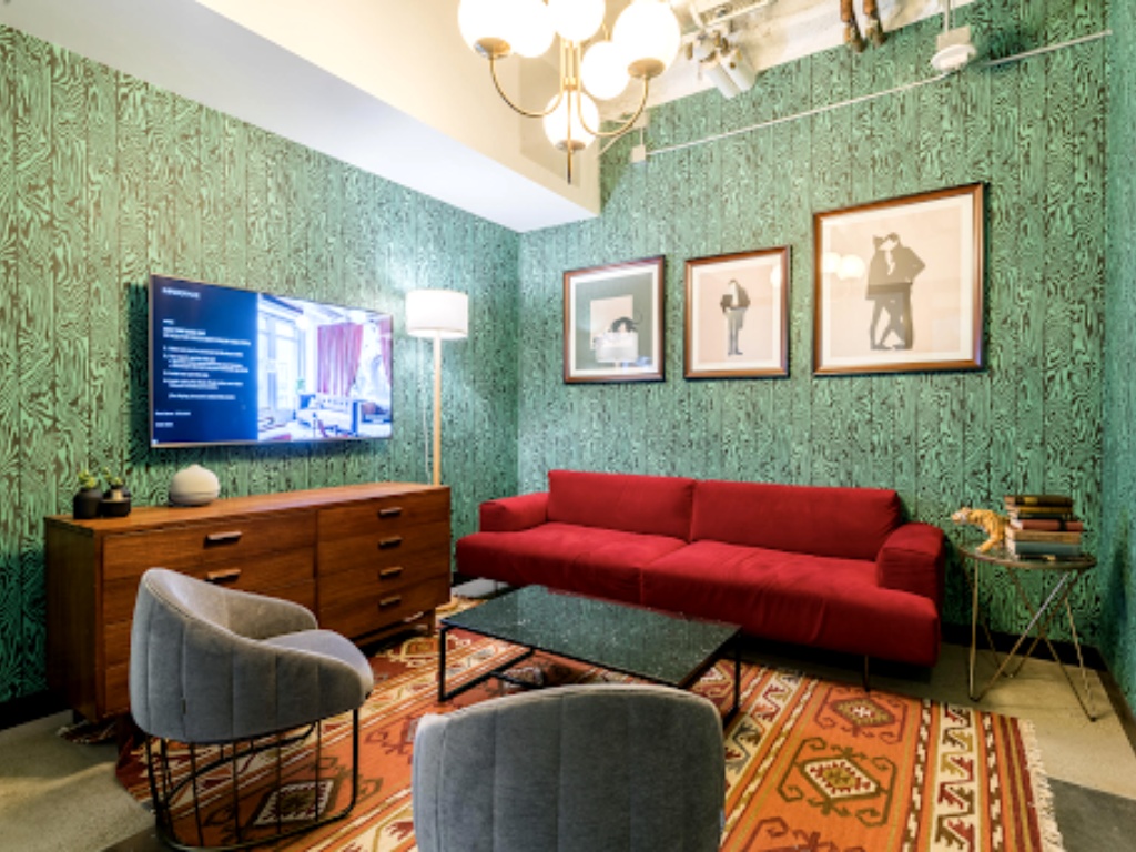 A lounge with patterned green walls, a red sofa and armchairs, shown in Oktana's Dreamforce 2022 meeting guide