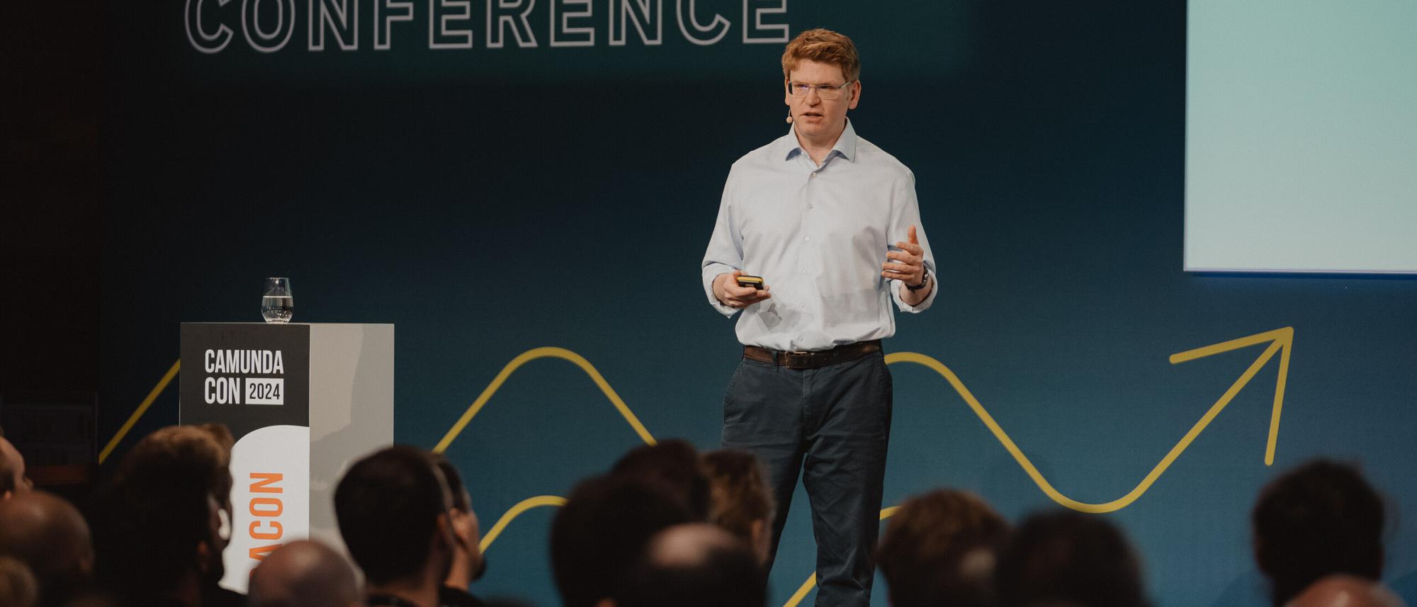 Jakob Freund speaking onstage to an audience at CamundaCon 2024 in Berlin