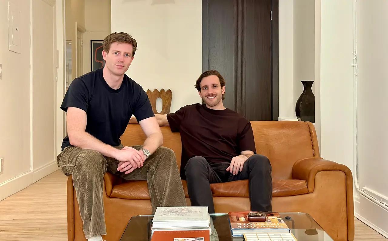 James Cadwallader, left, and Dylan Babbs seated together on a brown sofa